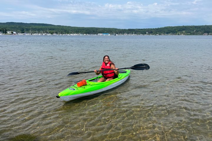 a girl wearing a lifejacket in georgian bay paddle in a green single kayak